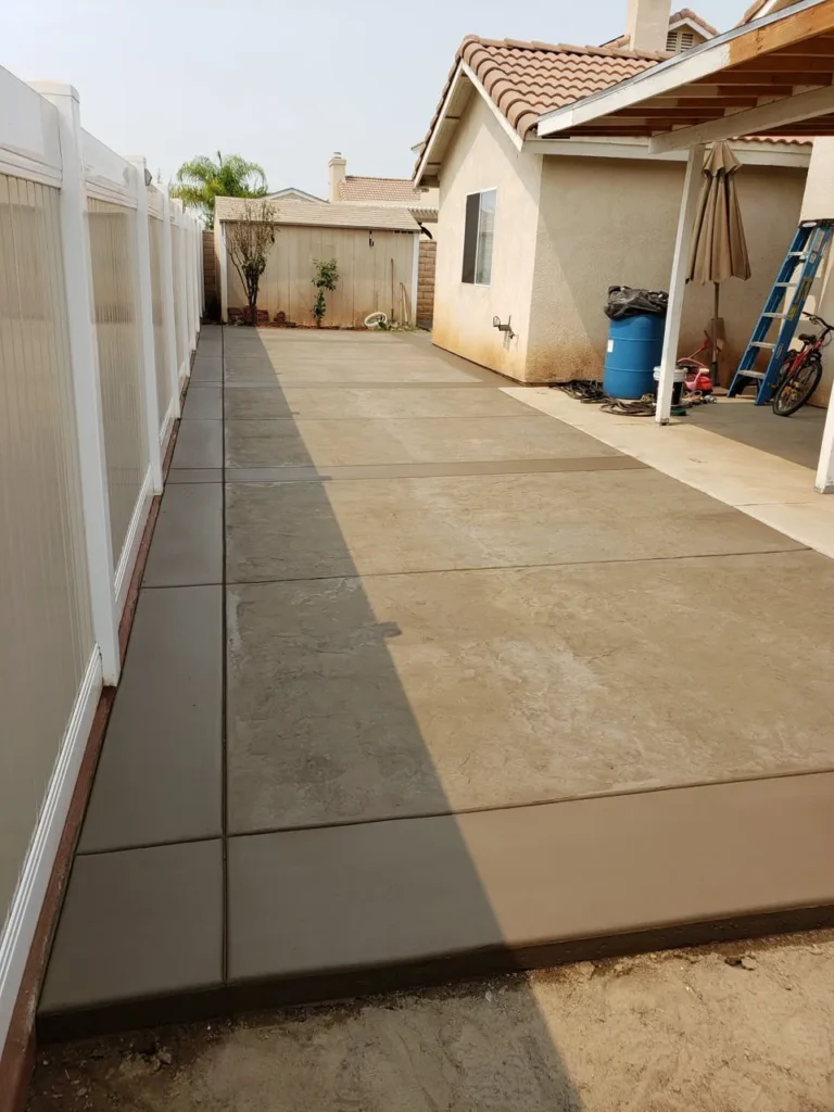 Long backyard concrete slab along a vinyl fence