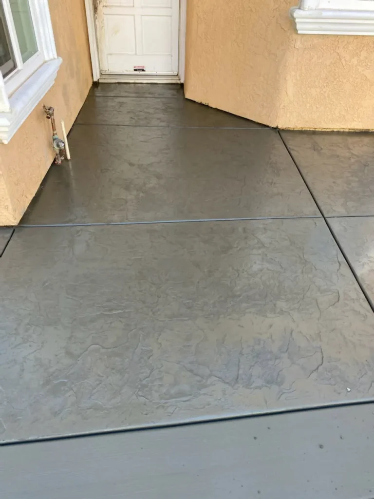 Freshly finished concrete patio slab beside a home